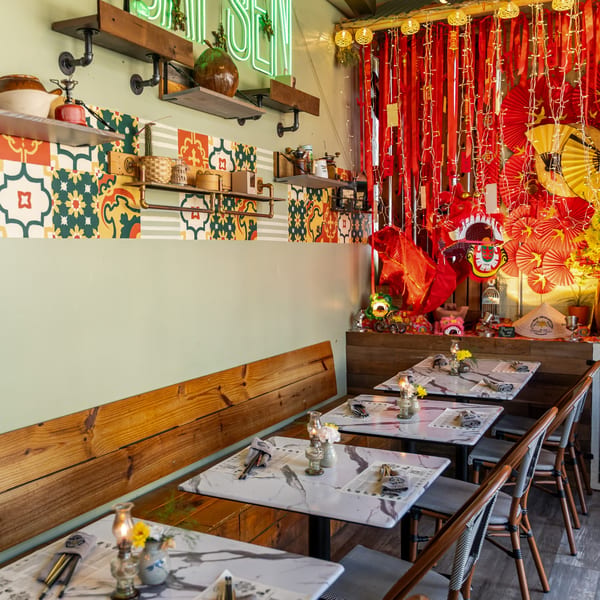 The interior of Sen Organic Small Plate, featuring a long wooden bench and tables with Vietnamese decor.