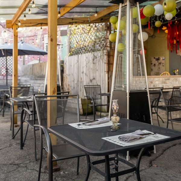 Outdoor patio dining area at Sen Organic Small Plate with black tables, chairs, and string lights.