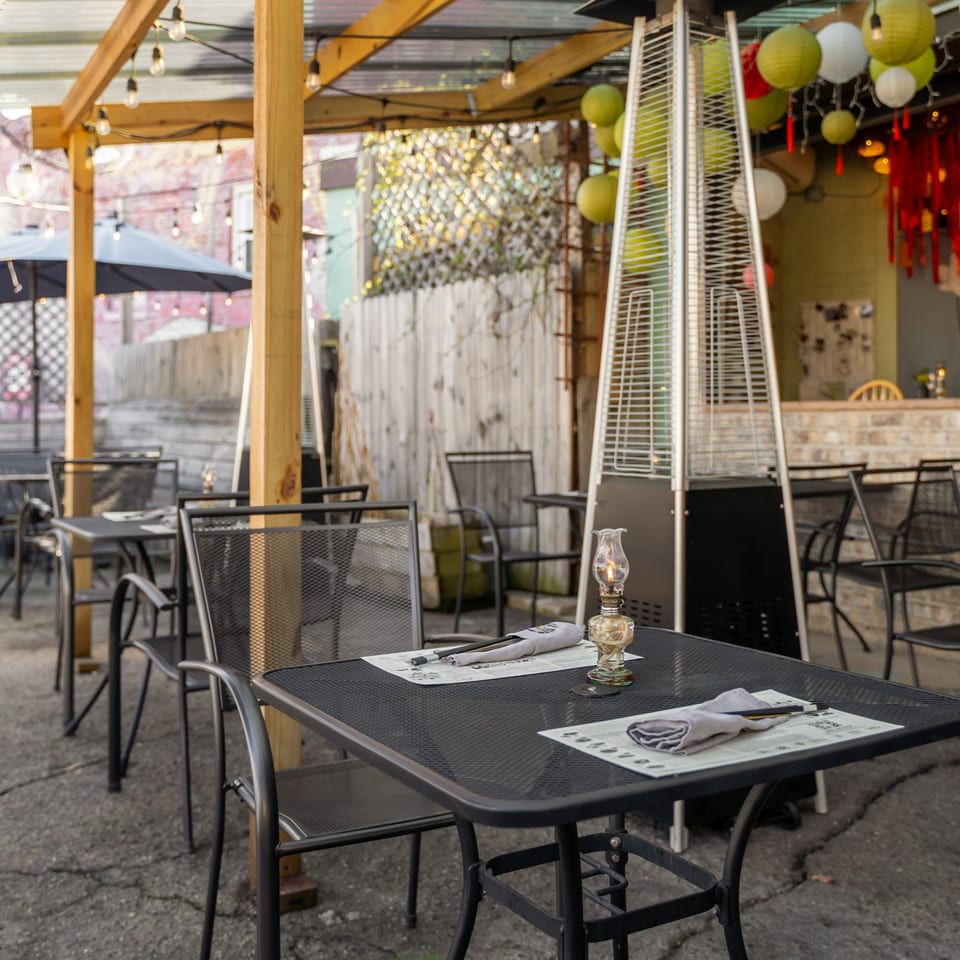 Outdoor patio dining area at Sen Organic Small Plate with black tables, chairs, and string lights.