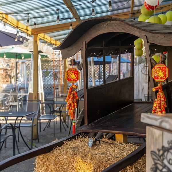 Outdoor patio at Sen Organic Small Plate with decorative hay, lanterns, and tables under a corrugated roof.